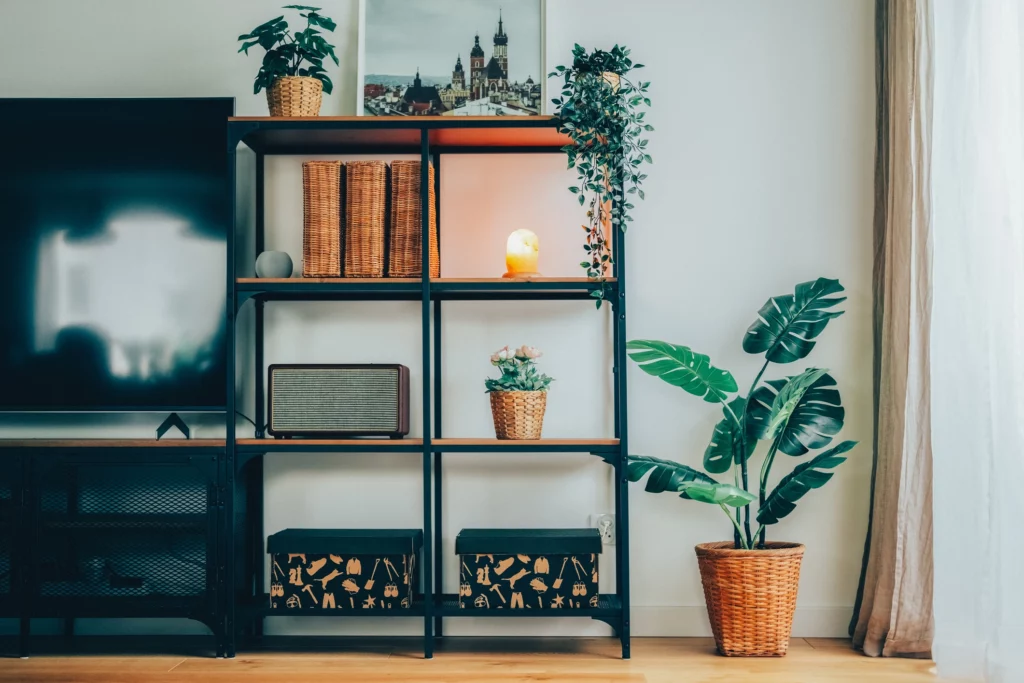 Imagem de um rack de aço industrial preto com algumas plantas e objetos decorativos para ilustrar matéria sobre ideias de rack para sala