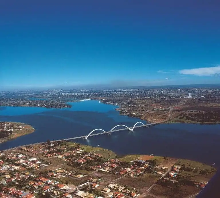 Imagem da vista aérea do Lago Paranoá mostra o lago, a ponte JK, residências e vegetação da cidade para ilustrar matéria sobre Brasília, o que fazer pela capital federal?