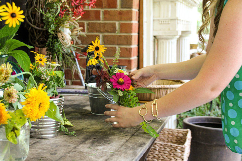 Imagem de uma mulher montando um arranjo com flores artificiais. 