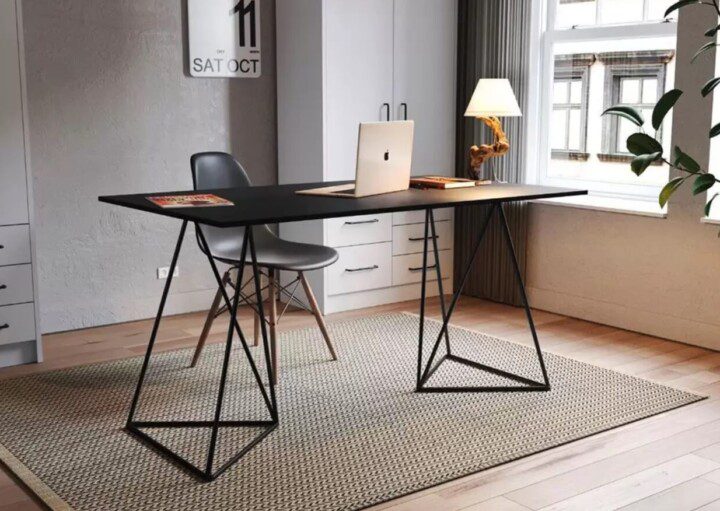 Um home office moderno com decoração de escritório moderna apresenta uma mesa preta, cadeira cinza, laptop, luminária, livros e tapete. Uma grande janela preenche o espaço com luz natural; armários brancos e uma planta verde iluminam o fundo.