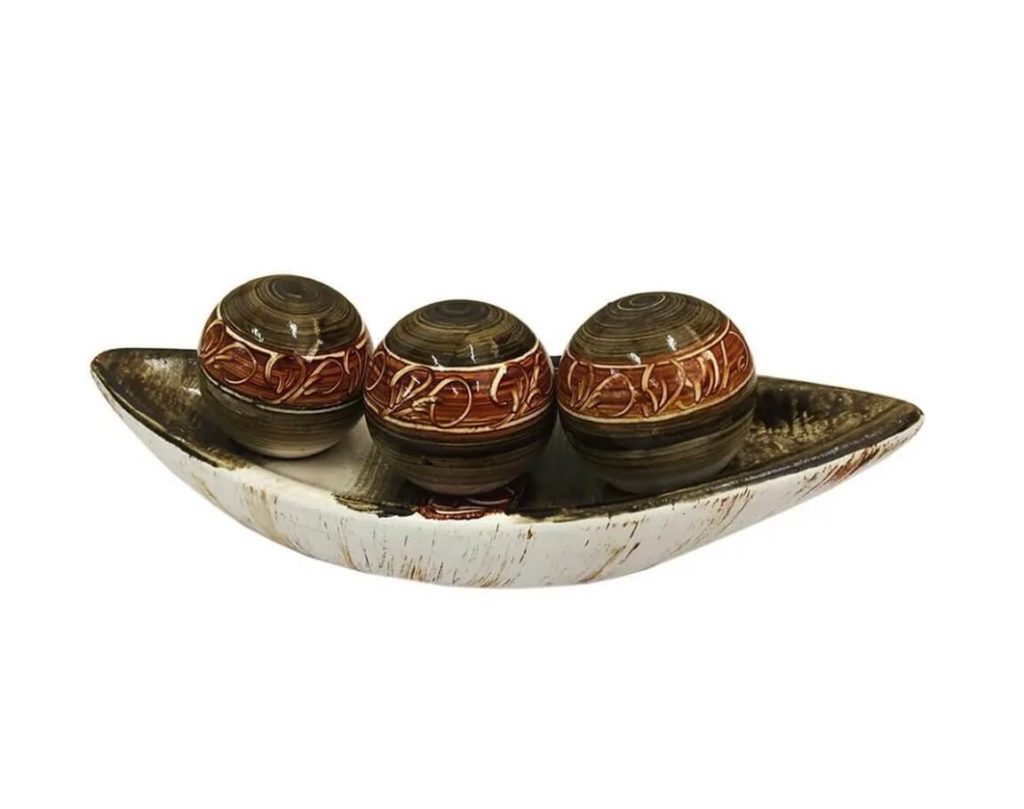 Foto que ilustra matéria sobre decoração de mesa mostra um enfeite decorativo de centro de mesa composto por um prato e três bolas pintados.