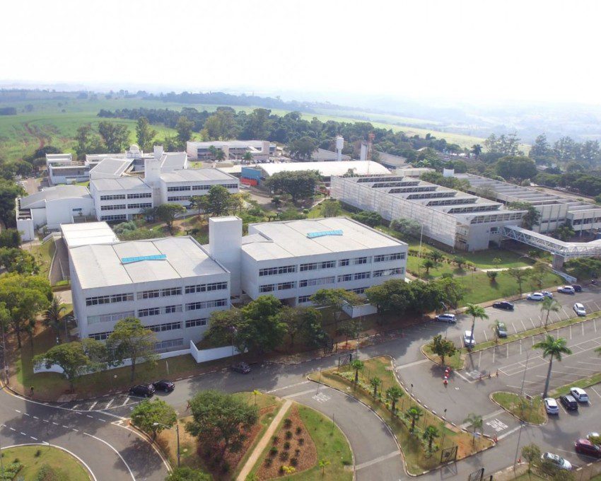 Foto que ilustra matéria sobre Faculdades em Campinas mostra uma visão aérea do Campus I da PUC-Campinas, um conjunto de prédios cercados por áreas de estacionamentos e áreas gramadas.