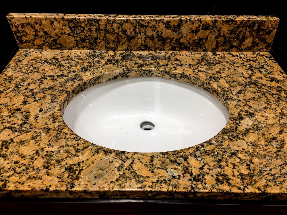 O granito amarelo Florença é o material usado para esta pia de banheiro.