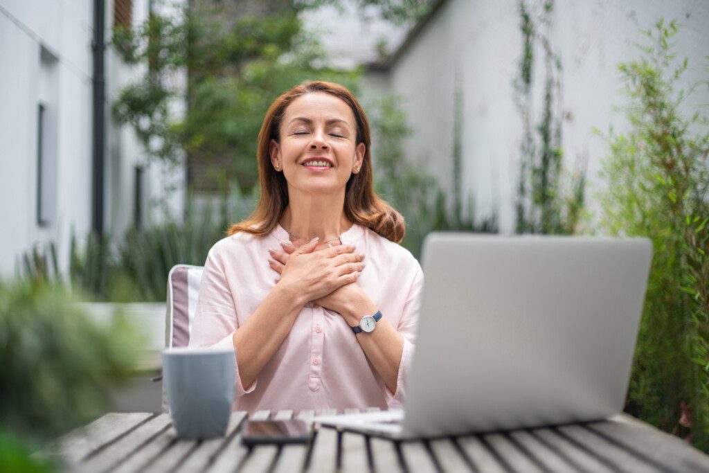 Mulher feliz recebendo boas notícias enquanto trabalhava em seu laptop.