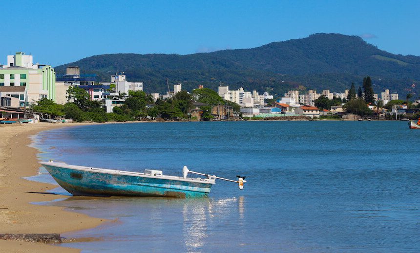 Foto que ilustra matéria sobre bairros em são josé mostra barreiros em são josé com o mar e um barquinho abarcado na areia