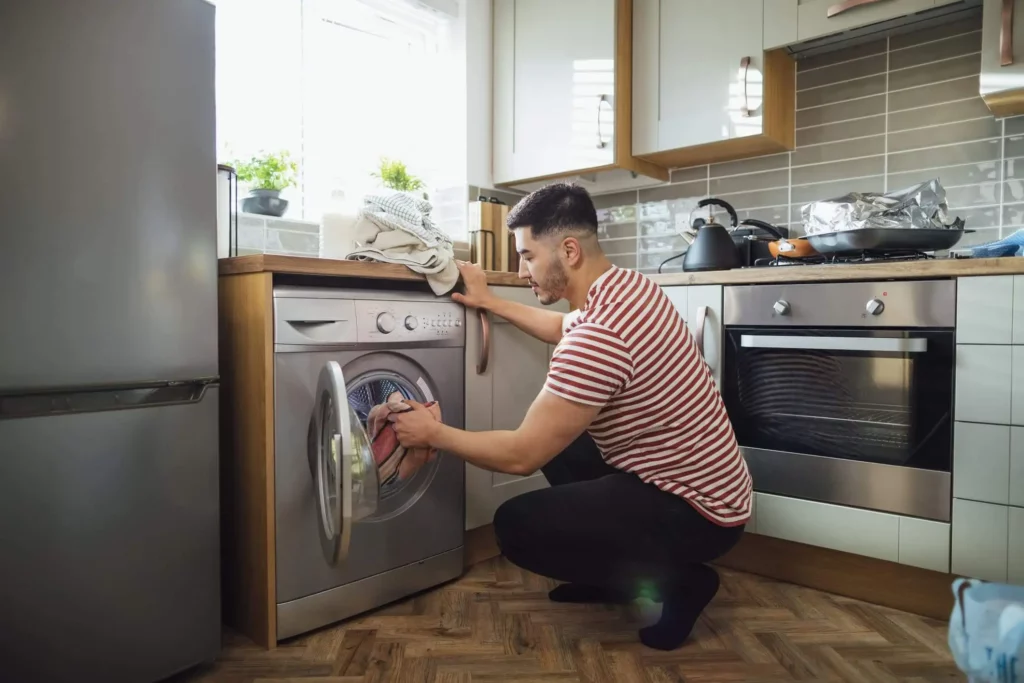 Imagem de um homem mexendo em uma máquina para ilustrar matéria sobre como higienizar máquina de lavar roupa