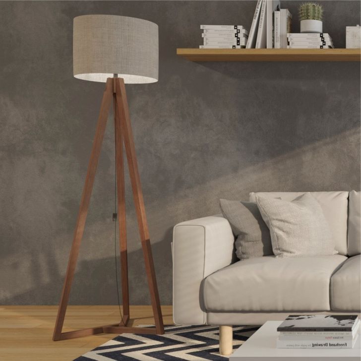 A foto mostra um exemplo de decoração retrô com luminária de chão. Ela tem pés de palito, assim como o sofá que está ao seu lado. Há também uma prateleira com livros acima do sofá. 