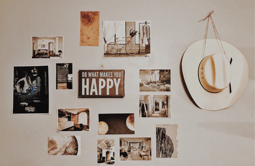 A foto mostra um exemplo de decoração retrô com diferentes placas decorativas e quadros na parede. Há também um chapéu de caubói pendurado.