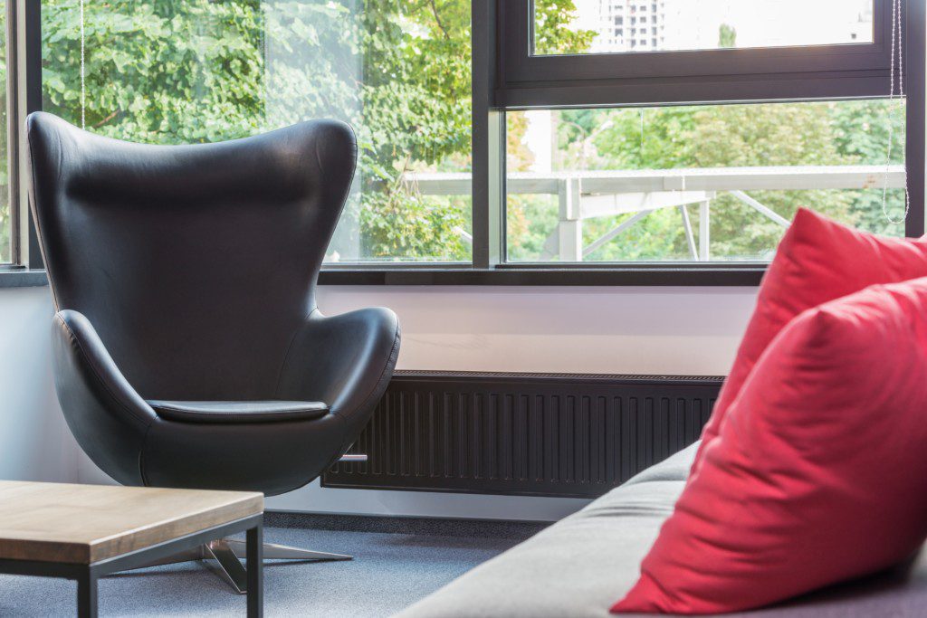 A foto mostra um exemplo de decoração retrô em uma poltrona preta com design conceitual. Há também um sofá com almofada vermelha.