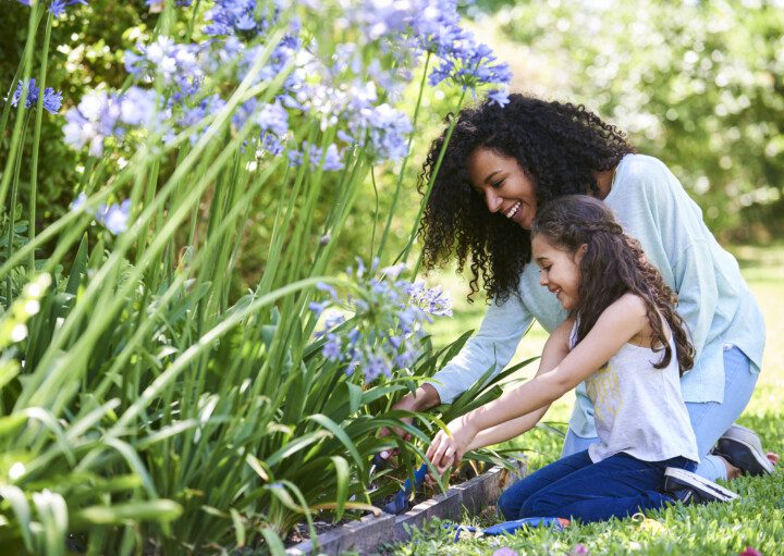 Foto que ilustra matéria sobre jardim no quintal mostra uma mulher e uma criança plantando em um jardim no quintal