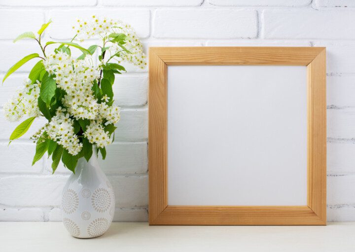 Imagem de um porta retrado com moldura de madeira ao lado de um vaso de flor.