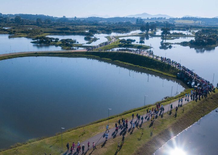 Foto que ilustra matéria sobre parque em Pinhais mostra uma visão do alto de vários lagos do Parque das Águas, com muitas pessoas andando pelos caminhos por entre eles.