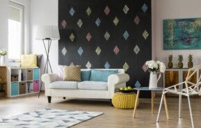 Foto que ilustra matéria sobre pinturas diferentes de parede mostra uma sala de estar com uma parede inteira de lousa, com losangos pintados com diferentes cores de giz.