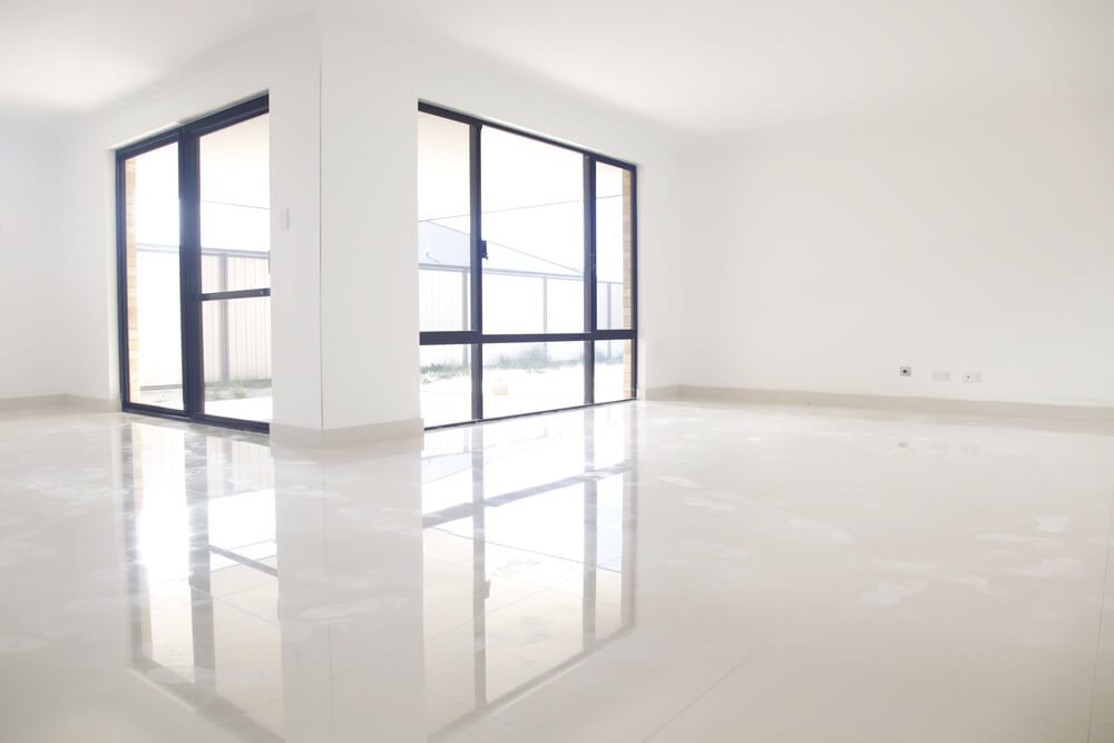 Piso de porcelanato claro em uma ampla sala de um imóvel vazio.