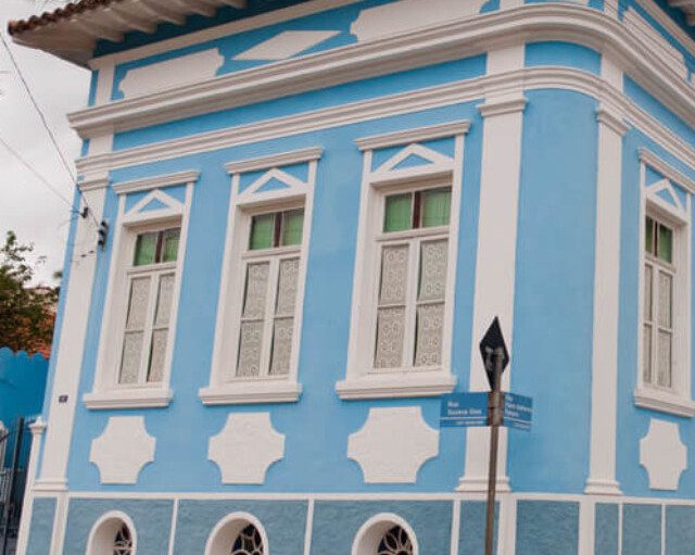 Foto que ilustra matéria sobre onde fica Santana do Parnaíba mostra um casarão histórico, um dos muitos tombados na cidade. A construção é toda azul clara, com detalhes em branco nas janelas e portas.