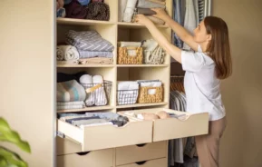 Imagem de uma mulher guardando panos de cama em um guarda roupa para ilustrar matéria sobre os benefícios de contratar um personal organizer