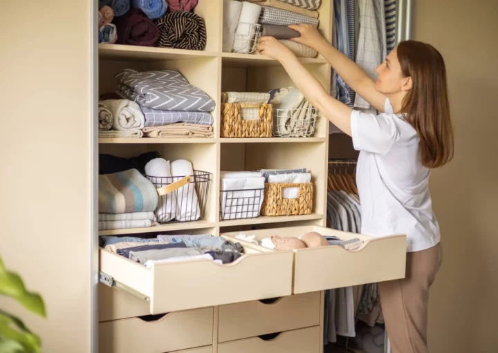 Imagem de uma mulher guardando panos de cama em um guarda roupa para ilustrar matéria sobre os benefícios de contratar um personal organizer