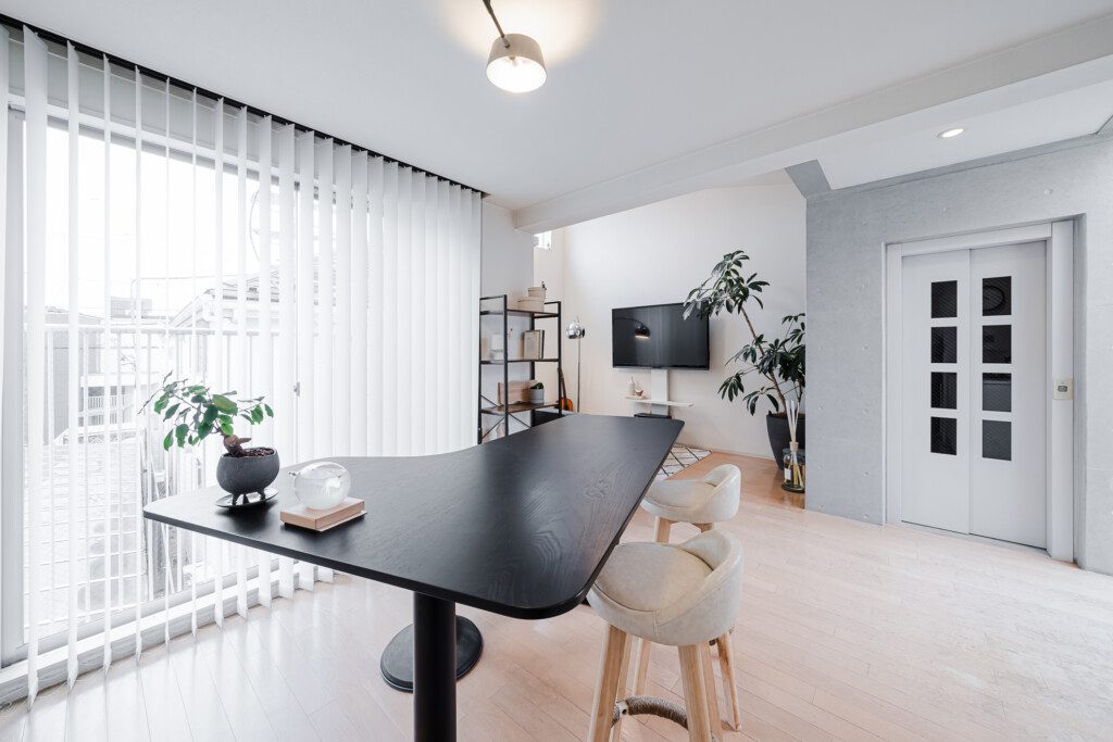 Sala de jantar com mesa elevada de estilo moderno. Há também cadeiras do tipo banquetas e outras decorações.