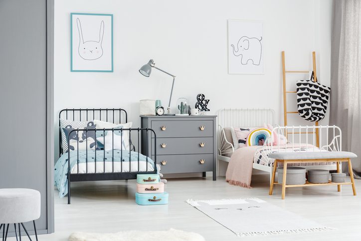 Quarto de dois filhos com uma cama em ferro preta e outra branca, cômoda cinza e decoração clean.