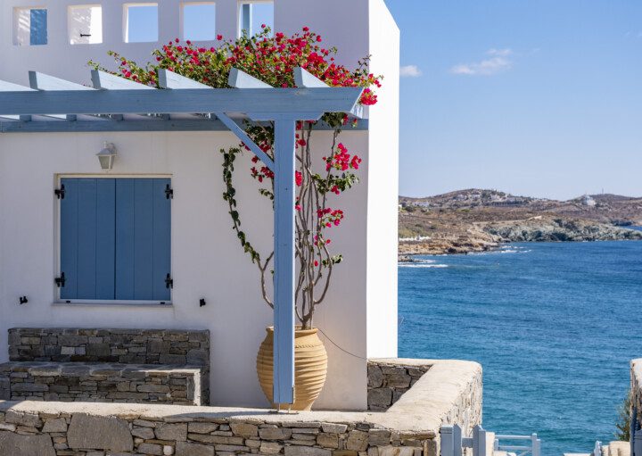 decoração de casa grega, na cor branca, com pergolado azul e flores rosas