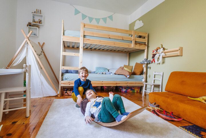 Imagem de dois meninos brincando em seu quarto.