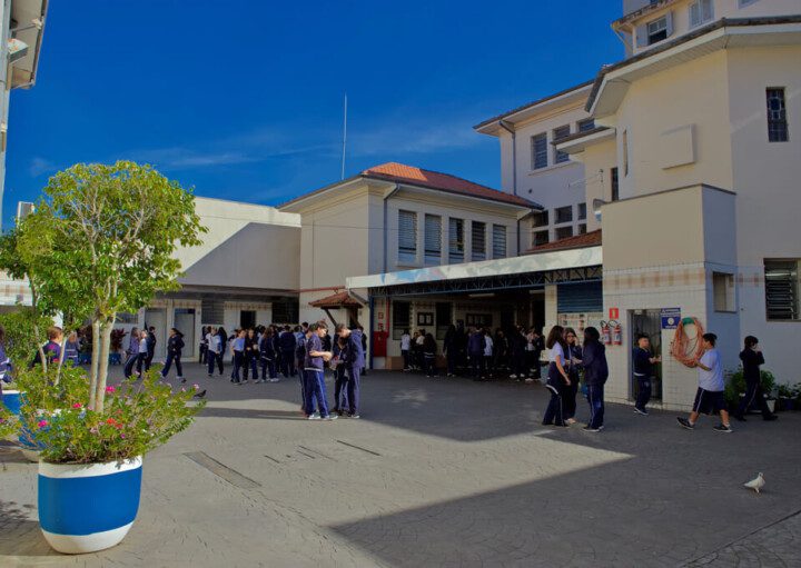 Foto que ilustra matéria sobre escolas particulares em Mogi das Cruzes mostra o pátio do Instituto Dona Placidina repleto de alunos em um dia de céu azul.