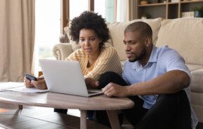 Foto que ilustra matéria sobre como escolher inquilino mostra um homem e uma mulher sentados em frente à um computador que está em uma mesa