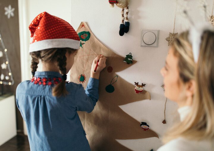 Imagem de mãe e filha decorando a casa para o Natal.