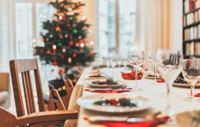 Imagem de uma mesa de Natal posta com uma árvore de Natal ao fundo.