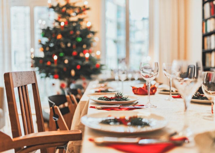 Imagem de uma mesa de Natal posta com uma árvore de Natal ao fundo.