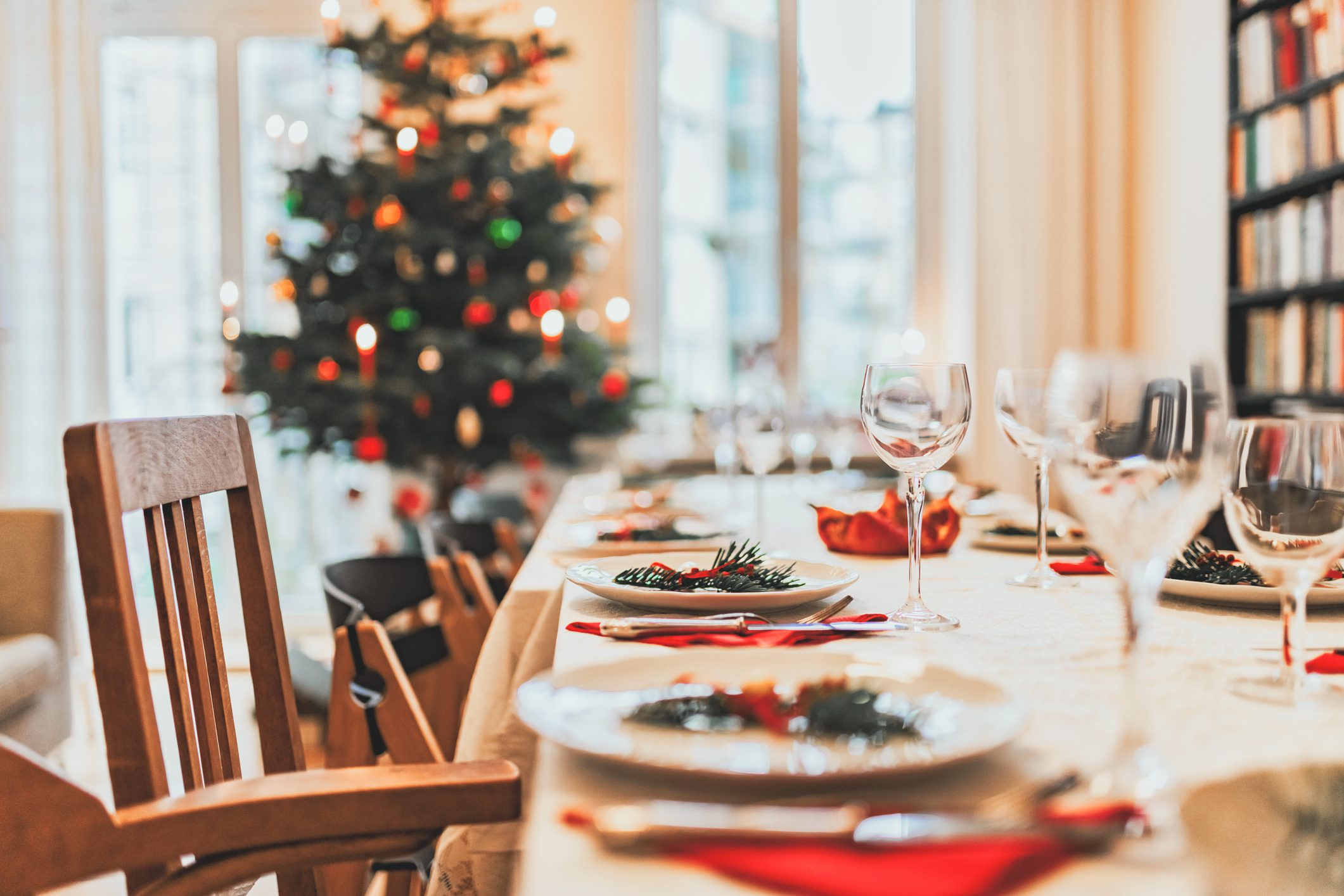 Imagem de uma mesa de Natal posta com uma árvore de Natal ao fundo.