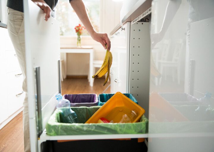 Imagem de uma pessoa separando o lixo e jogando uma casca de banana na lixeira correta.