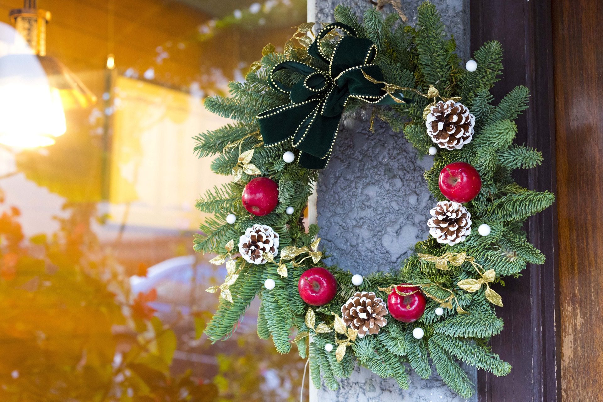 Guirlanda de Natal com frutas artificiais e laço fixada na parede.