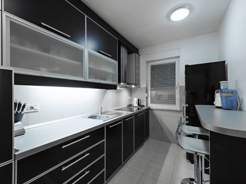 Cozinha com decoração em estilo gótico. Móveis pretos com detalhes brancos.