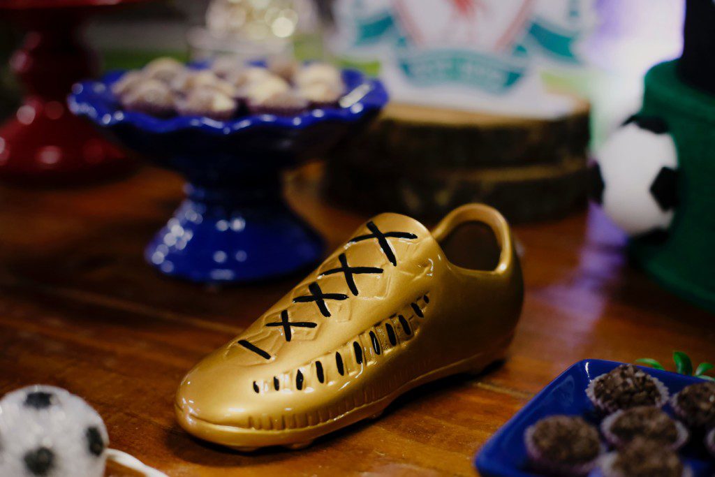 Mesa de festa de aniversário com chuteira de futebol comestível.