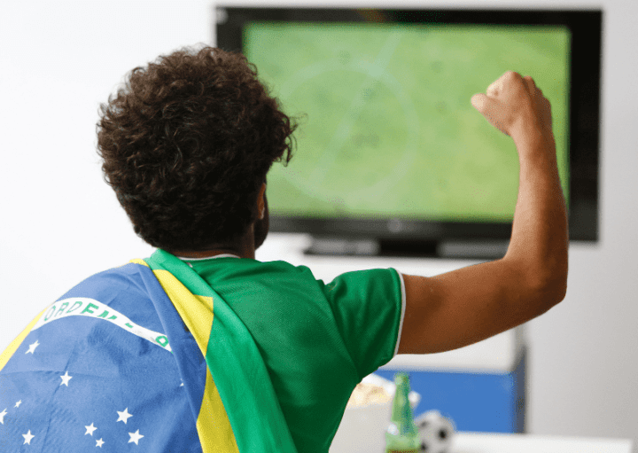 Torcedor do Brasil vibra em frente ao aparelho de televisão.