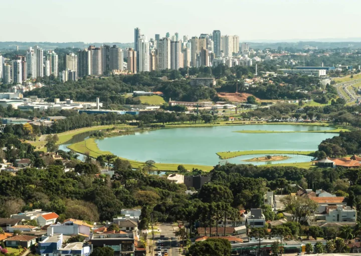 Imagem da vista aérea de Curitiba mostra lago, parque, vegetação, casas e prédios ao fundo para ilustrar matéria sobre qual o bairro mais seguro de Curitiba