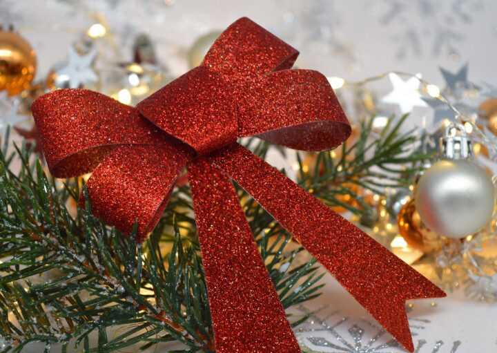 Laço de Natal vermelho junto com alguns galhos, bolas e luzes,