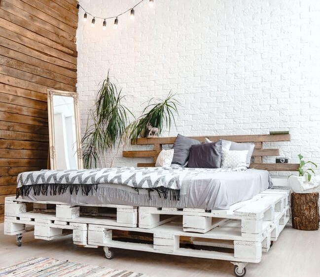 Aqui, a base da cama feita de palete ganha a sofisticação das rodinhas