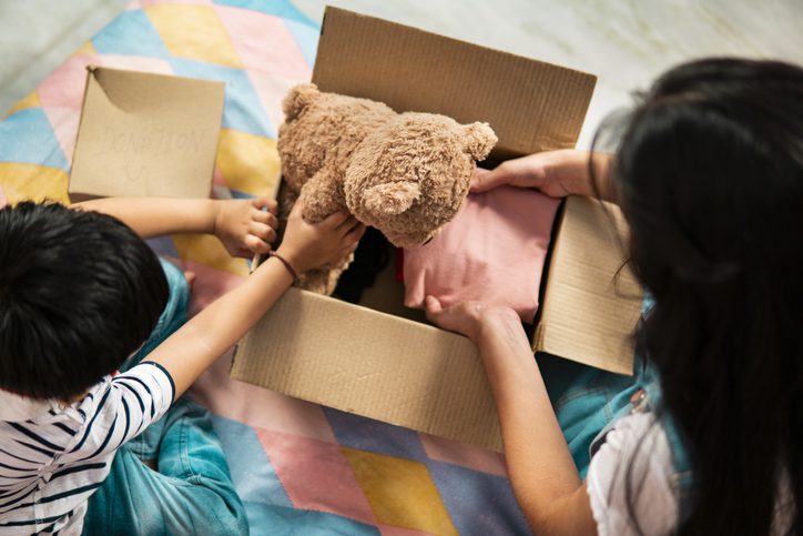 Irmão e irmã guardando um urso dentro de uma caixa de papelão.  