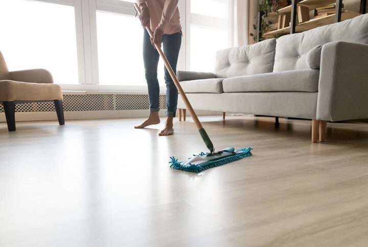 Imagem de uma mulher limpando o chão da casa com um Mop de limpeza.