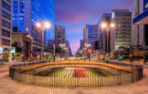 Foto que ilustra matéria sobre o que fazer em SP mostra um viaduto da Avenida Paulista à noite, com prédios altos iluminados em ambos os lados.