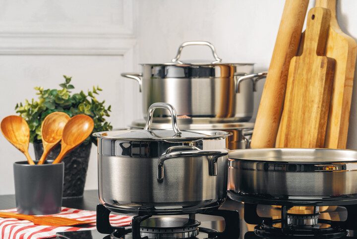 Imagem de panelas de alumínio, utensílios de cozinha e tábuas de madeira.