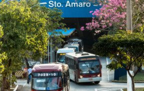 Foto que ilustra matéria sobre o Terminal Santo Amaro mostra diversos ônibus saindo de dentro de dentro do local onde ficam os pontos. Acima deles se vê o letreiro do terminal.