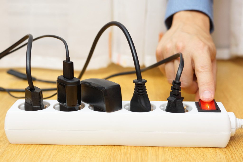 Foto de uma pessoa fazendo o desligamento de aparelhos elétricos em uma extensão.