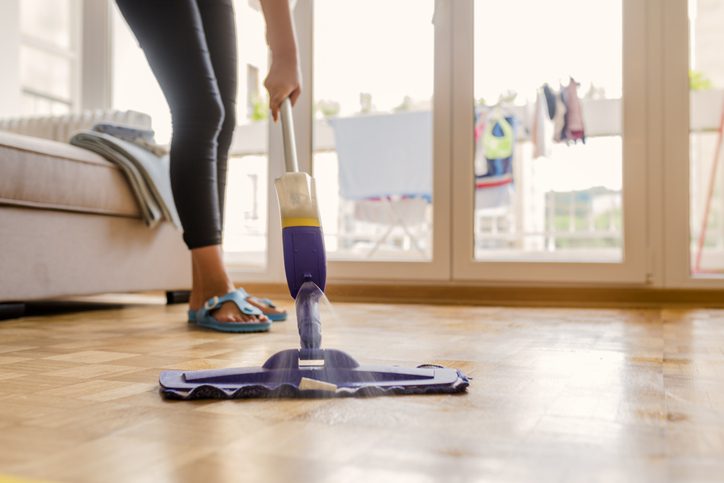 Imagem de uma mulher limpando o chão com um Mop modelo de spray.