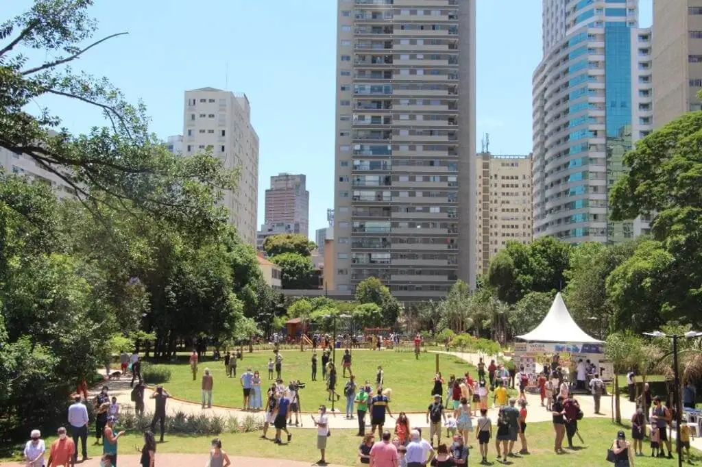 Imagem de pessoas no gramado do Parque Augusta, que é rodeado por prédios, para ilustrar matéria sobre os parques de São Paulo