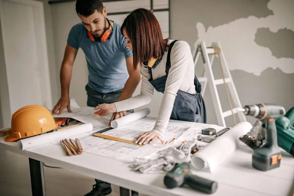 Imagem de dois engenheiros olhando a planta de um imóvel em um canteiro de obras para ilustrar matéria sobre quanto custa reformar um apartamento de 40m2