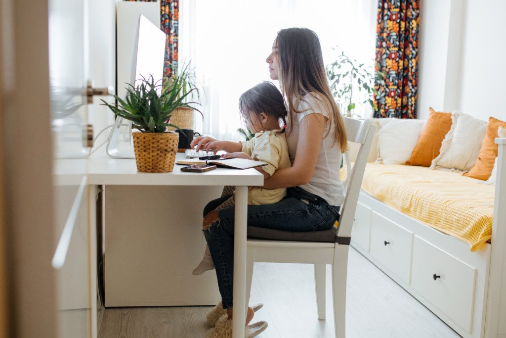 Mãe e filha juntas em um escritório compartilhado com quarto de visitas. Imagem disponível em Getty Images.