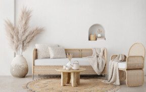 Sala com decoração estilo boho em tons de bege e madeira com vaso decorativo, almofadas e mesa de centro.